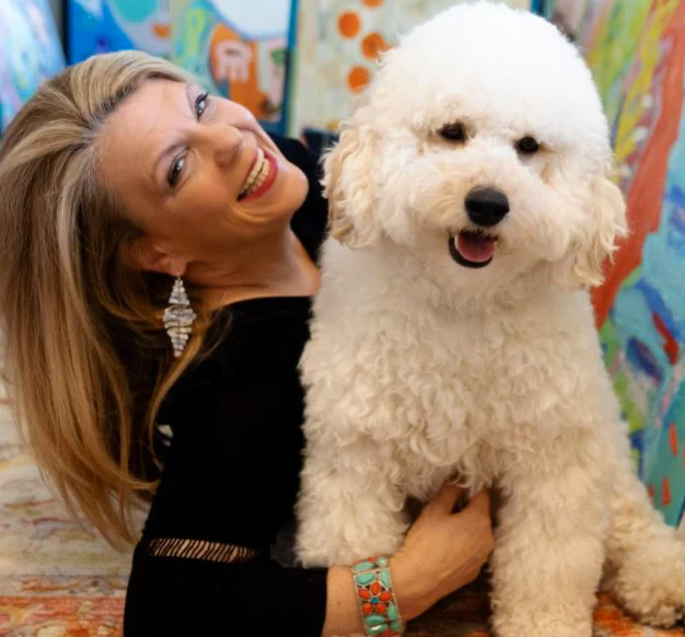 Artist Aleea Jaques smiles while holding her golden doodle.