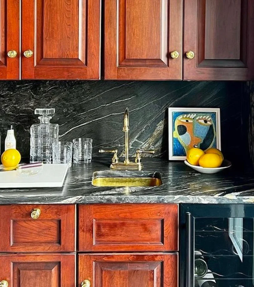 An abstract portrait sits on the dark marble counter of a wet bar.