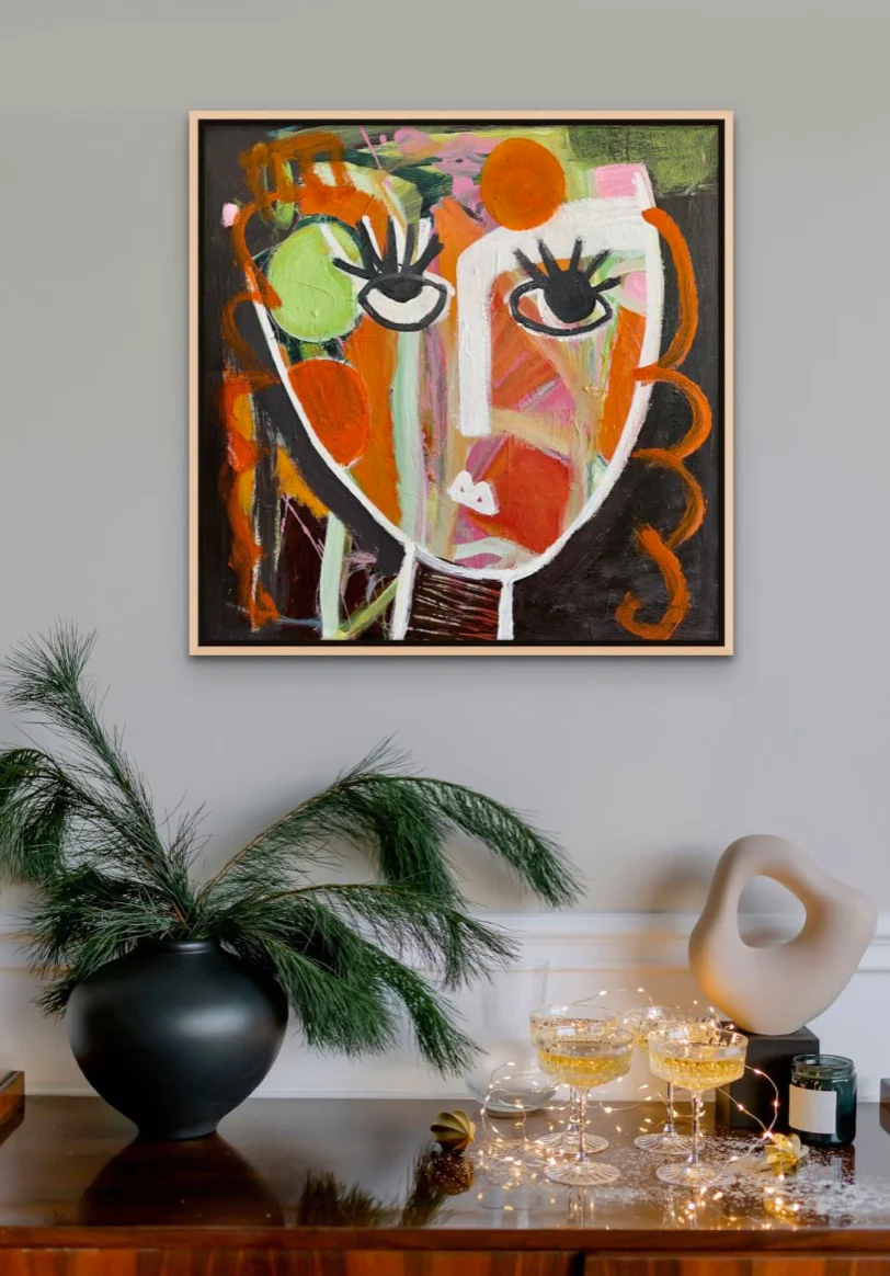 An abstract portrait painted in deep, rich colors hangs in a contemporary living room.