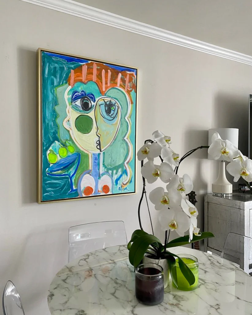 A colorful abstract portrait painting hangs in a contemporary kitchen.